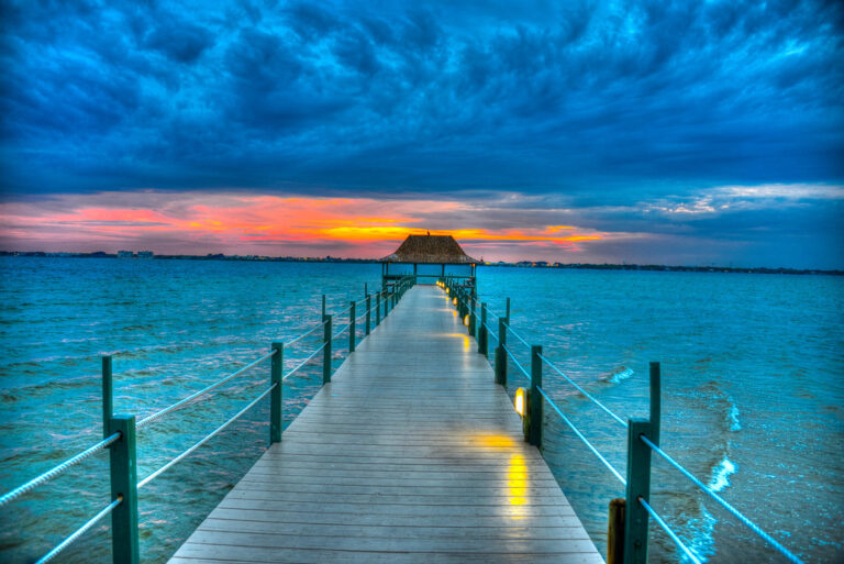 Illuminated pier over water at sunset